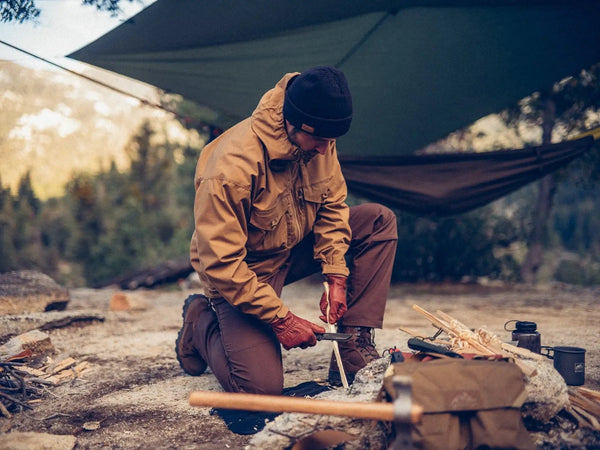 Eine Person, die gerade Feuer macht mit Helikon-Tex Gear