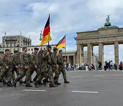 Bundeswehrsoldaten laufen mit zwei Deutschlandflaggen vor dem Brandenburger Tor.